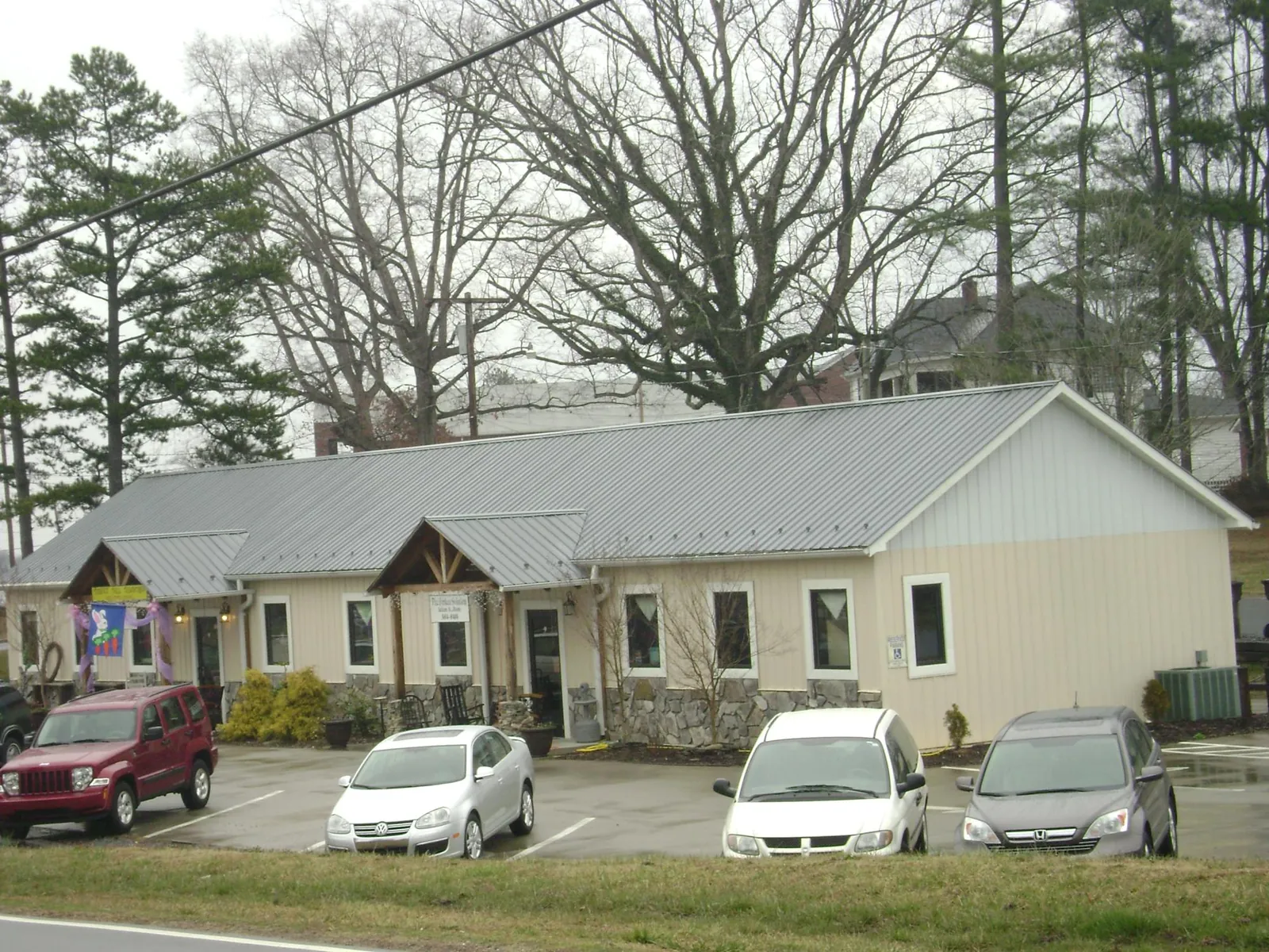 Gray metal roof with timber entry brackets on a small commercial building in Wolcott