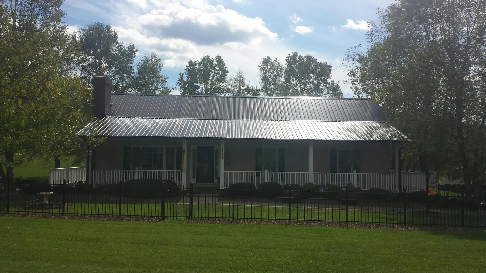 Gray metal roof on a brick ranch with a full width front porch — Gutter Guard Installation work by our crew in Wolcott